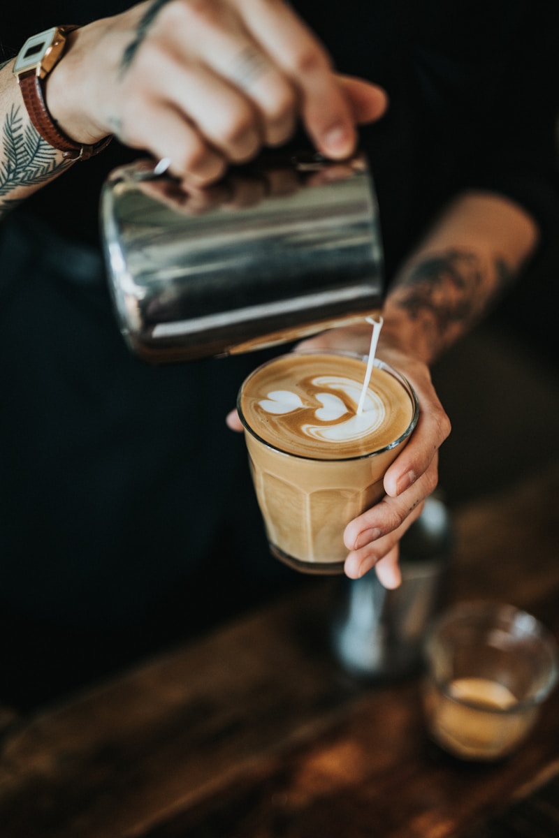 man pouring milk in coffee